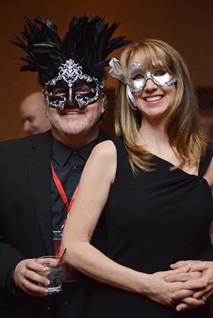 一个男人和女人为相机微笑，一边打扮，戴着蒙面的球口罩。