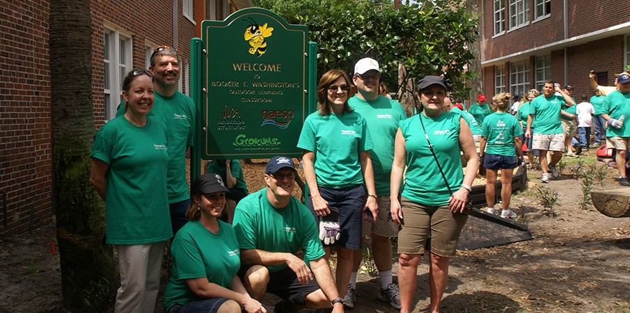 志愿者游乐场建造者在一个欢迎标牌旁边站立到一个新的公园。