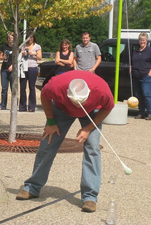 景观结构员工玩一场比赛，他必须用网球从附着在他的头上悬挂的网球晃来敲打水瓶。