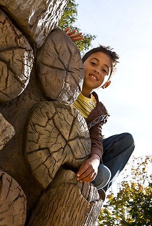 微笑对照相机的一个男孩，当倾斜在有木五谷手举行的日志堆登山者时。