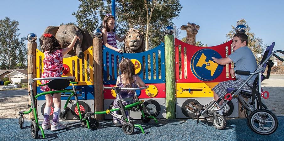 三个孩子在一个以包容性动物园为主题的操场上在感官触及面板上玩。