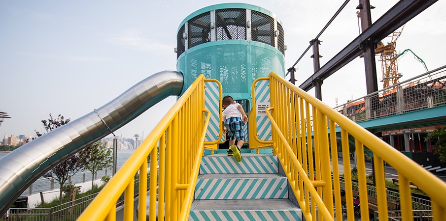 一个男孩沿着一些游乐场台阶前往多米诺公园的Sweetwater Silo Playground结构。