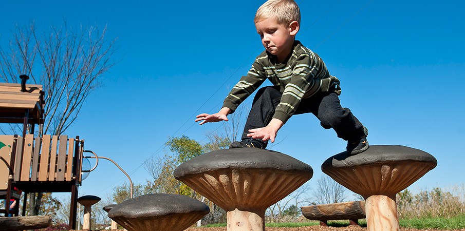 一个年轻的男孩从一个蘑菇步进到下一个。