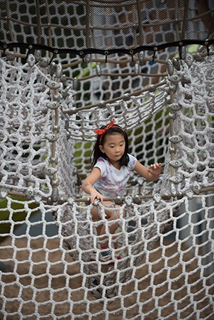 在法国地区公园，一个女孩正从一个货物网迷宫中爬出来。