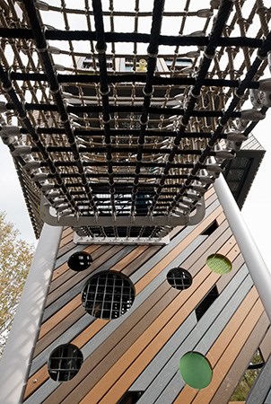独特的游乐场塔的侧面，由真实的和可回收的木板制成，带有尖顶的感官孔。