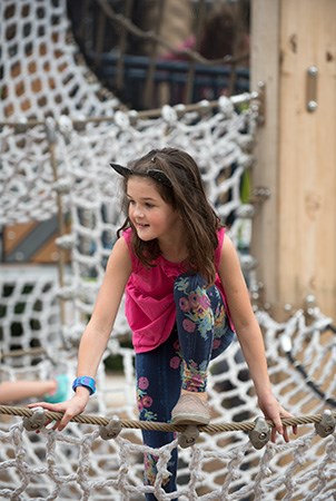 一个女孩爬上了游乐场的吊货网。